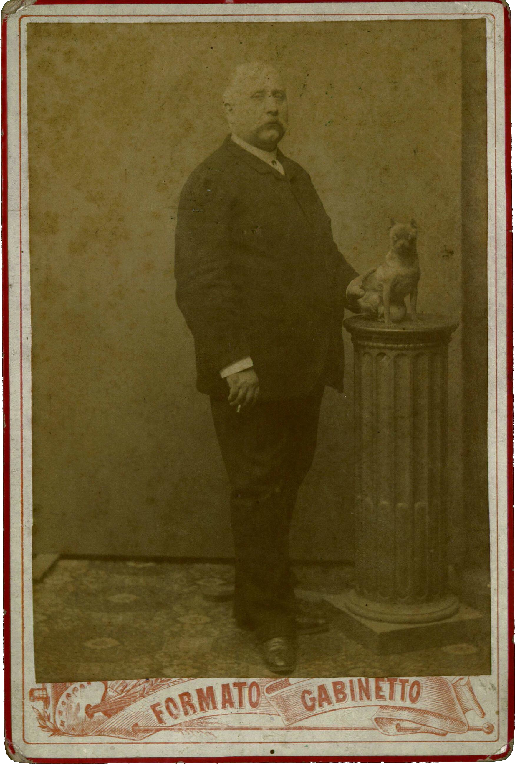 Luigi Capuana accanto ad una colonnina con sopra la cagnetta di G. Verga